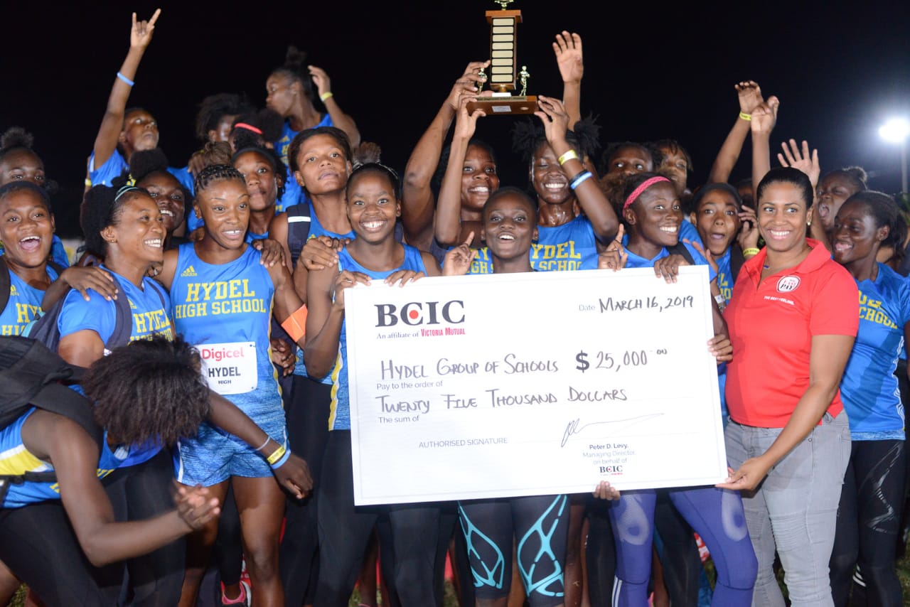 Hydel High Track & Field team being presented with a trophy and symbolic cheque by Lori- Ann Glasgow- GM, Marketing (BCIC).