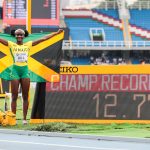 Kerrica Hill poses at the clock to celebrate her 12.77 championship record on Saturday's (6 Aug) final day of the Cali22 World Athletics U20 Championships in Colombia.